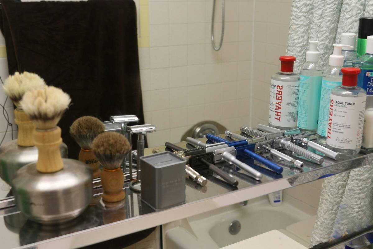 Hand holding high-quality shaving brush creating rich lather with shaving accessories for traditional shaving