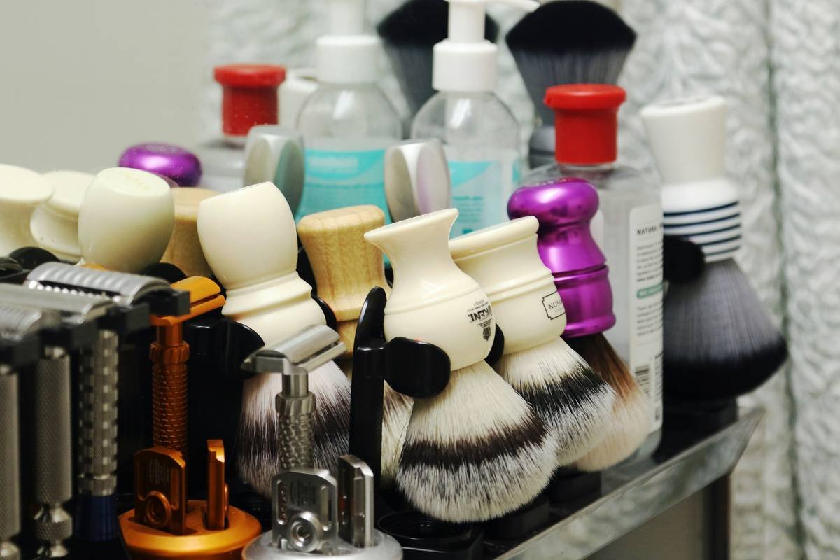 Premium shaving brush set and accessories including badger brush, stand, bowl, and travel case on wooden surface
